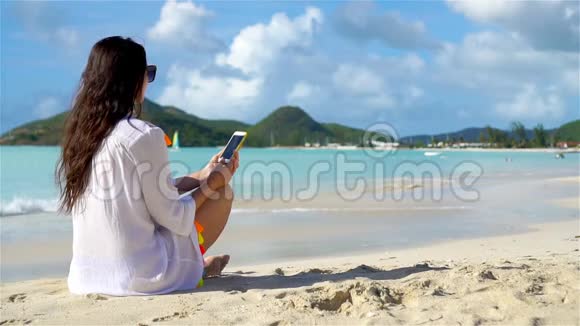 带智能手机的年轻女性在热带海滩度假加勒比海上有手机的海滩美女视频的预览图