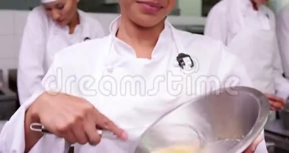 微笑的厨师在碗里搅拌鸡蛋视频的预览图