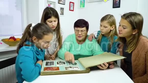 祖母和四个孙女在家看旧相册视频的预览图