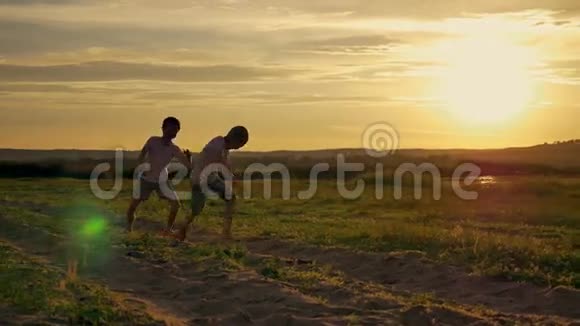 两个快乐的孩子在公园里跑来跑去在田野上两兄弟正在日落时分玩耍视频的预览图