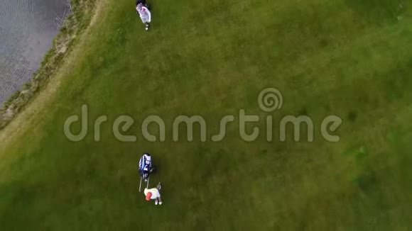 空中观景高尔夫球场高尔夫球手在球道上用高尔夫球袋和手推车行走视频的预览图