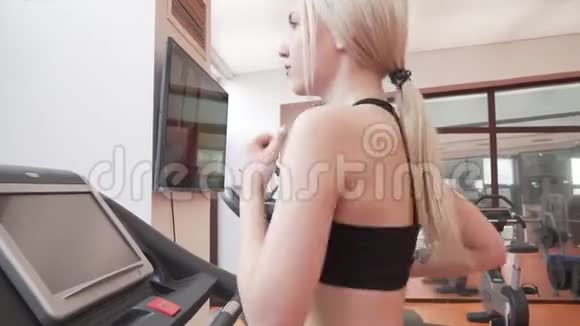 年轻女孩在健身房的跑步机上训练股票录像视频的预览图