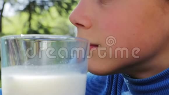 一个健康的孩子和一杯牛奶的肖像一个男孩在大自然中喝牛奶健康的饮食正确的方法视频的预览图