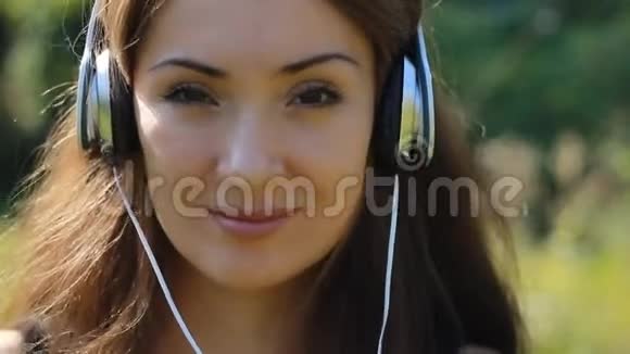 微笑的女人用耳机听音乐视频的预览图