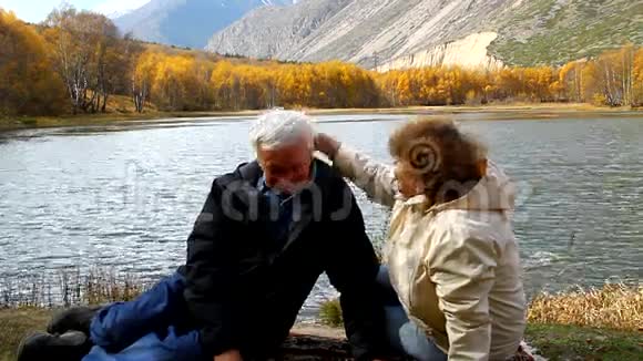 快乐成熟的男人和女人坐在湖边视频的预览图