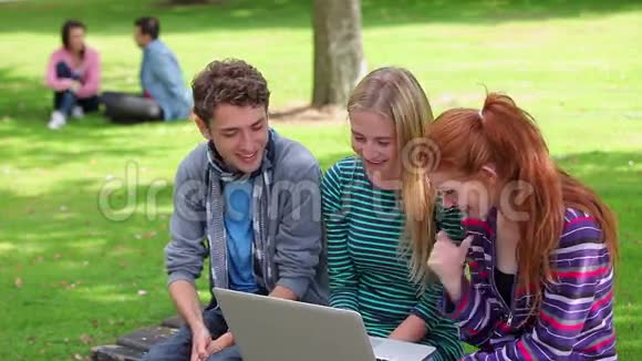 三个学生一起看着笔记本笑着视频的预览图
