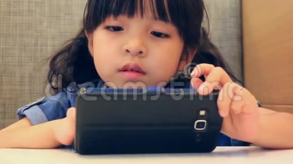 可爱的亚洲女孩玩智能手机视频的预览图