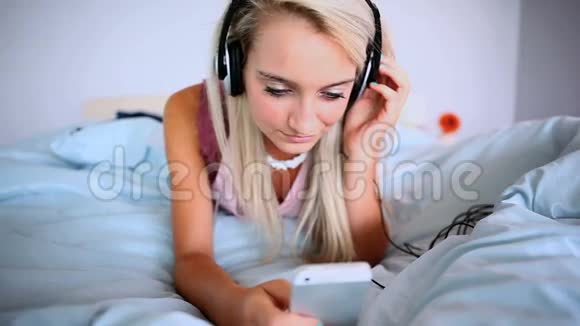 迷人的金发女郎听音乐躺在床上视频的预览图