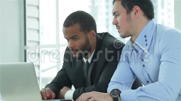 两个成功的商人在他的笔记本电脑上工作视频的预览图