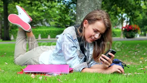 快乐的学生躺在草地上发短信视频的预览图