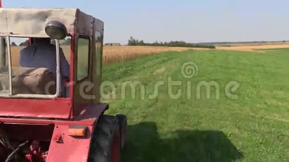 农夫开着红色的旧拖拉机在农村农场之间视频的预览图