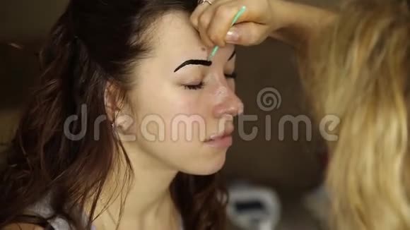 化妆师用画笔画出漂亮女孩模特的眉毛视频的预览图