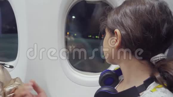 少女航空飞机概念年轻女孩坐在窗边的飞机上看着生活方式夜间飞行视频的预览图