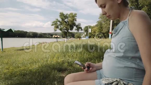 在公园使用手机的孕妇视频的预览图