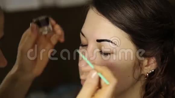 化妆师用画笔画出漂亮女孩模特的眉毛视频的预览图