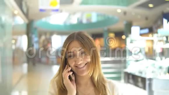 漂亮的年轻女人在商场打电话视频的预览图
