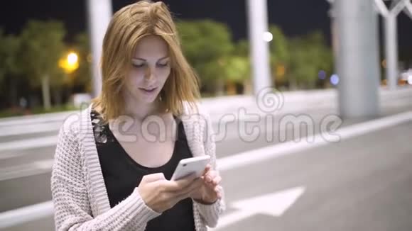 有魅力的女人在夜城街头散步时使用手机视频的预览图