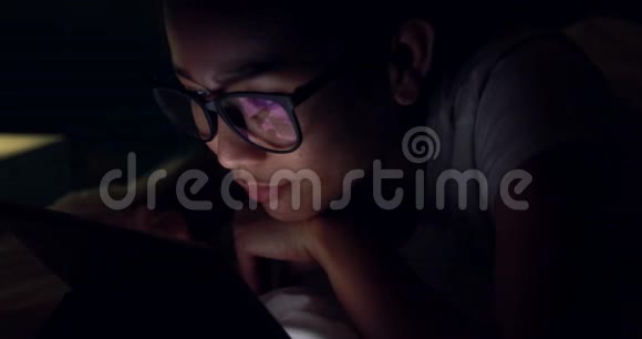 在床上玩手机或智能手机的亚洲年轻女子夜晚视频的预览图