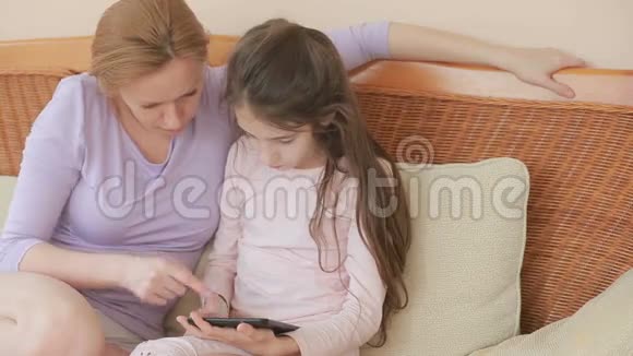 一位美丽的母亲和她的小女儿说得很好母亲拿着一块药片教她的女儿视频的预览图