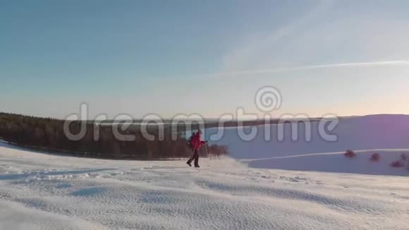 一个人背着背包背着跋涉的棍子在冬天的群山背景下美丽的日落山上的雪A视频的预览图