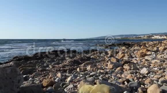 肮脏的岩石海滩上装满了塑料瓶和纸垃圾在海滩上堆垃圾慢动作视频的预览图