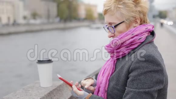 女人在河边用智能手机视频的预览图
