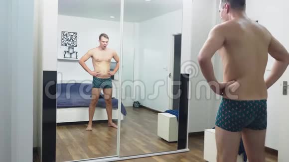 年轻人在卧室的镜子前检查自己的肌肉视频的预览图