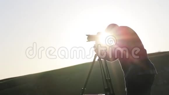 摄影师用相机和三脚架在山顶上拍摄视频的预览图
