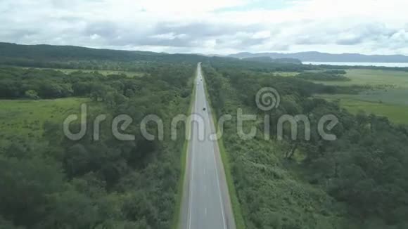 阳光明媚的一天汽车沿着空旷的乡村道路行驶上面的鸟瞰图视频的预览图