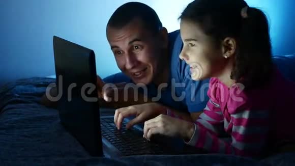 十几岁的女孩和男人爸爸和女儿在笔记本电脑上工作在网上玩娱乐游戏视频的预览图