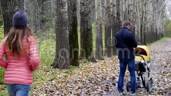 爸爸妈妈带着一个新生婴儿在树林里散步视频的预览图