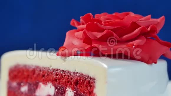 带有巧克力装饰的白色蛋糕和深蓝色背景的红色杏仁糖玫瑰装饰着可食用红玫瑰的蛋糕视频的预览图