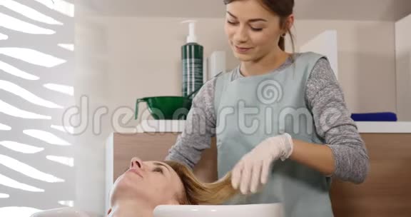 现代水疗中心的头发护理在发廊的理发师洗头发的女人女人在水疗中心洗头水疗中心视频的预览图