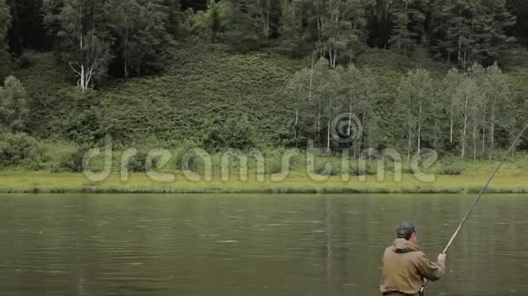 快乐的渔夫正在岸边平静的河水中捕鱼视频的预览图