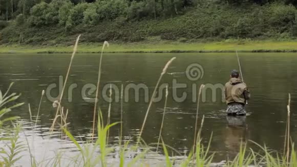 快乐的渔夫正在岸边平静的河水中捕鱼视频的预览图