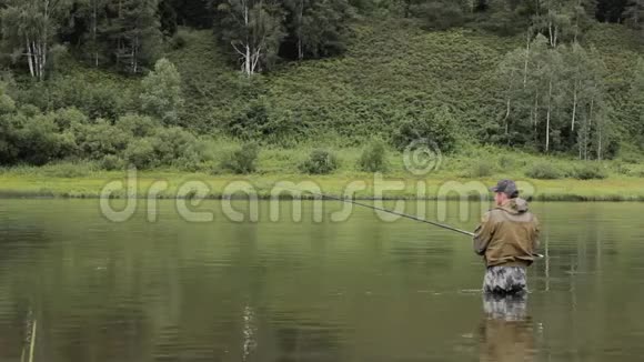 快乐的渔夫正在岸边平静的河水中捕鱼视频的预览图