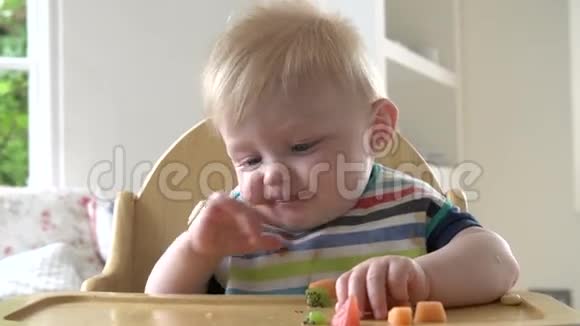 坐在高椅子上吃水果的男婴视频的预览图