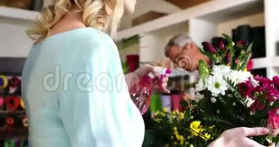 花店女花匠在花束上喷水视频的预览图