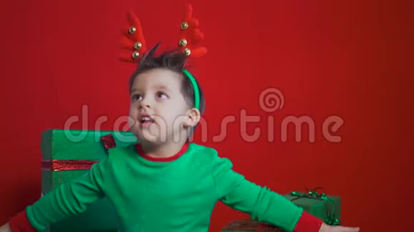 穿着绿色小矮人服装的孩子坐在装有鹿角的礼盒上视频的预览图