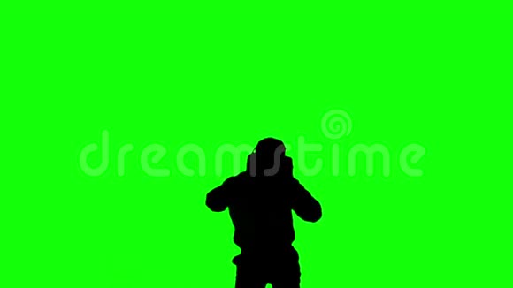 一个人在绿色屏幕上跳跃和听音乐的剪影视频的预览图