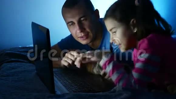 十几岁的女孩和男人的父亲和女儿在笔记本电脑上工作在网络娱乐游戏中玩互联网视频的预览图