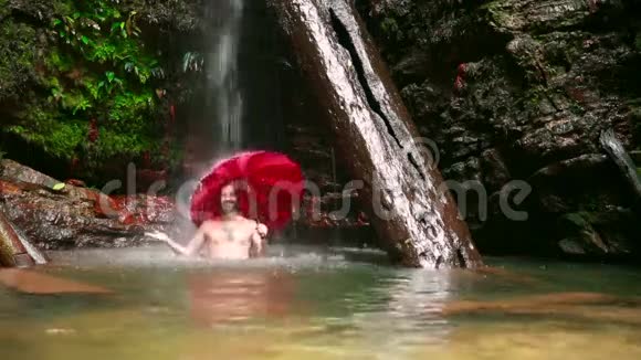在婆罗洲热带雨林的瀑布中带着伞的人视频的预览图