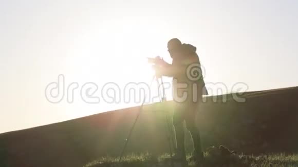 摄影师用相机和三脚架在山顶上拍摄视频的预览图