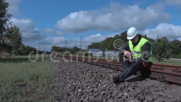 铁路工人坐在铁轨上使用平板电脑和对讲机视频的预览图