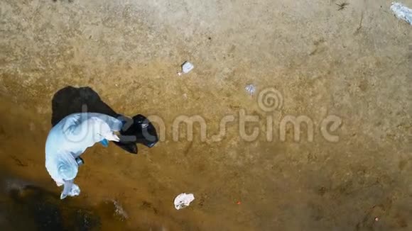 在干燥污染的河流岸边收集塑料垃圾的人穿着防护服和呼吸器的鸟瞰图视频的预览图