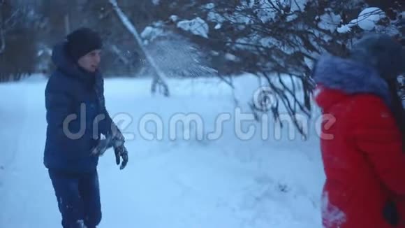 一对年轻夫妇在冬季公园散步一个男人和一个女孩在公园的雪地里玩耍视频的预览图