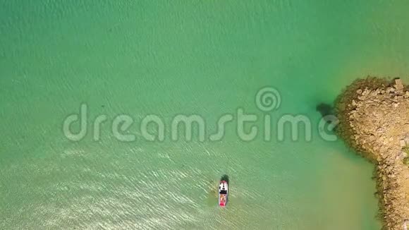 俯视船在透明的海水中航行从在绿松石海水中航行的飞行无人机船上可以看到空中景色视频的预览图