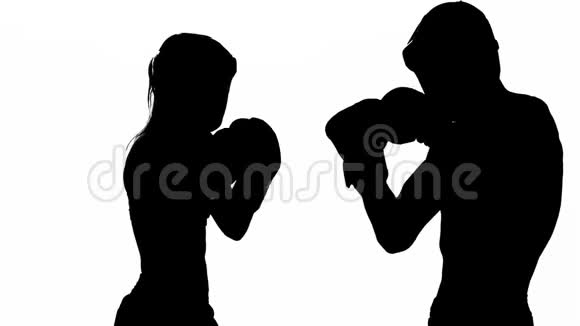 女人在踢他们正在为踢拳击而争吵的家伙剪影白色背景慢动作视频的预览图