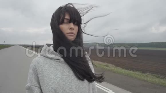 女人走在空荡荡的乡村道路上视频的预览图