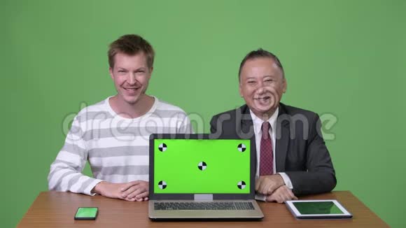 成熟的日本商人和年轻的斯堪的纳维亚商人一起工作视频的预览图
